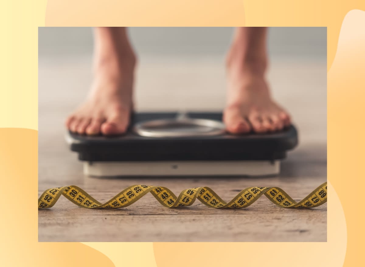 close-up of person's feet on scale and a measuring tape in front of the scale