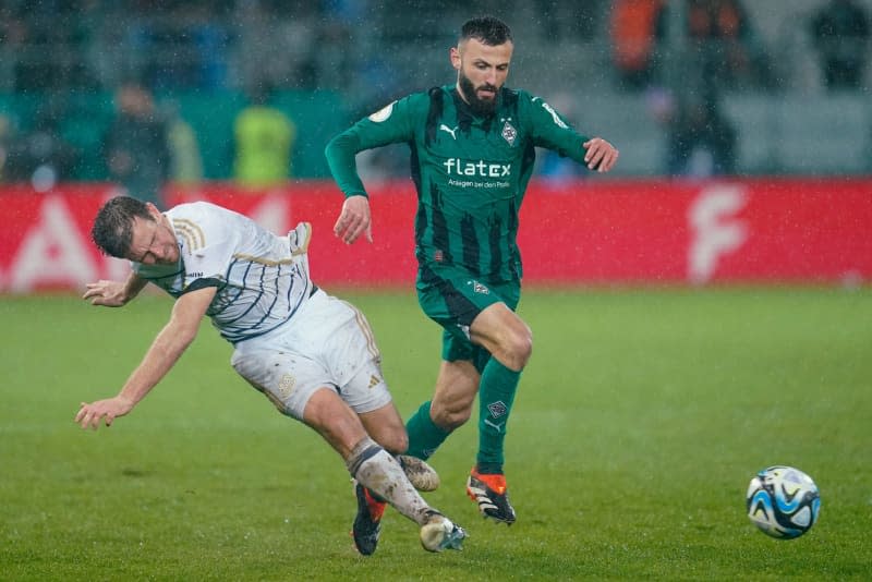 Saarbruecken's Manuel Zeitz (L) and Moenchengladbach's Franck Honorat battle for the ball during the German DFB Cup quarter final soccer match between 1. FC Saarbruecken and Borussia Moenchengladbach at Ludwigspark Stadium. Uwe Anspach/dpa