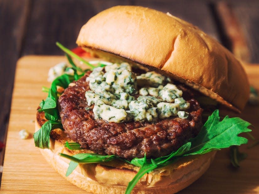 burger on a bun with arugula and blue cheese