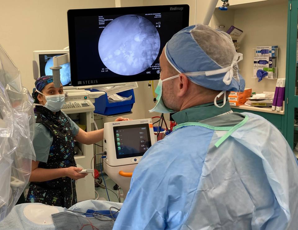 Kelsey Huddleson, a LECOM Health radiation technician, uses a remote to turn on electrodes that Dr. Matthew "Casey" Becker has threaded into the patient's renal artery. The procedure, renal denervation, was done April 25 at Millcreek Community Hospital to reduce chronically high blood pressure.