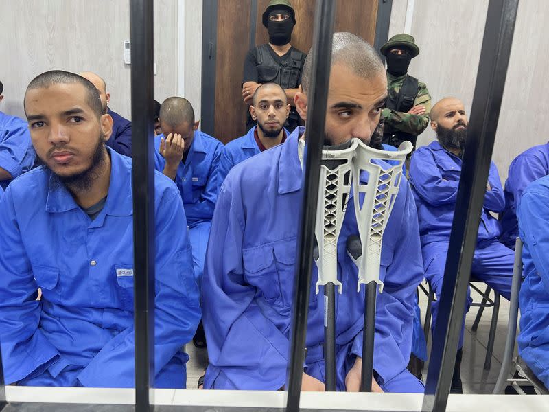 Suspects sit behind bars during a judgment sentence against 56 defendants accused of joining Islamic State group in the court in Misrata