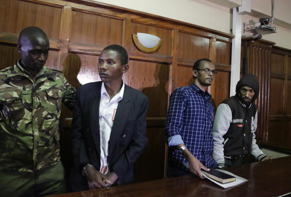 From left to right, defendants Rashid Charles Mberesero, Hassan Aden Hassan and Mohamed Abdi Abikar, are led from the dock by a police officer, left, after their verdict at a court in Nairobi, Kenya Wednesday, June 19, 2019. The Kenyan court found Mberesero, Hassan and Abikar guilty of conspiracy to commit a terror attack after phone records and handwriting linked them to the 2015 Garissa University assault that killed 148 people, while a fourth person, Sahal Diriye Hussein, was acquitted. (AP Photo/Khalil Senosi)