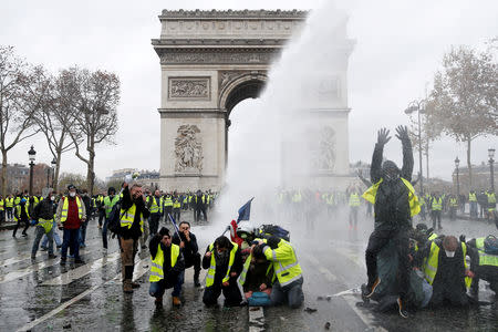 FILE PHOTO: Protesters wearing yellow vests, a symbol of a French drivers' protest against higher diesel taxes, stand up in front of a police water canon at the Place de l'Etoile near the Arc de Triomphe in Paris, France, December 1, 2018. REUTERS/Stephane Mahe/File Photo