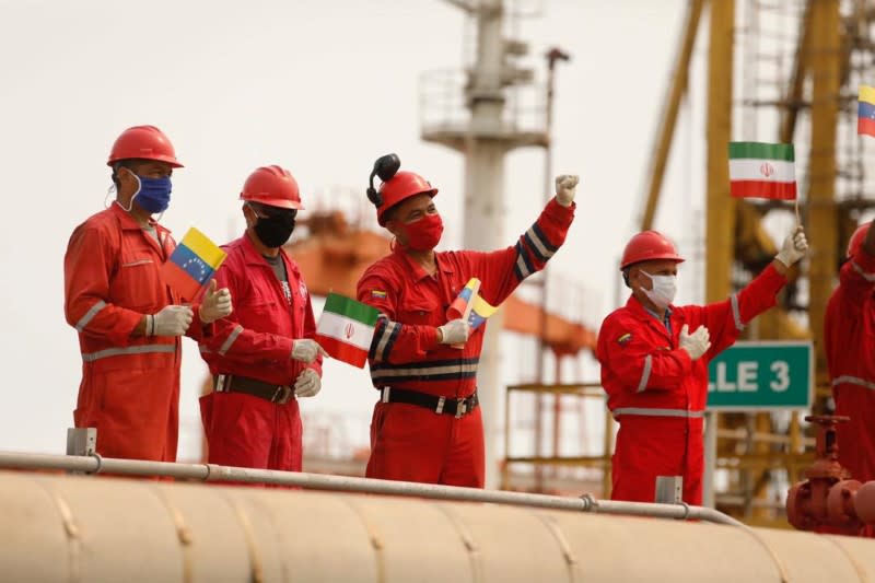 Workers of the state-oil company Pdvsa holding Iranian and Venezuelan flags greet during the arrival of the Iranian tanker ship "Fortune" at El Palito refinery in Puerto Cabello