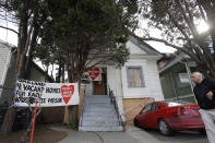 A man walks in front of a house that was occupied by homeless women in Oakland, Calif., Tuesday, Jan. 14, 2020. Homeless women ordered by a judge last week to leave a vacant house they occupied illegally in Oakland for two months have been evicted by sheriff's deputies. They removed two women and a male supporter Tuesday from the home before dawn in a case highlighting California's severe housing shortage and growing homeless population. (AP Photo/Jeff Chiu)