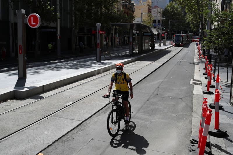 A man rides his bike by an almost empty area of the city following the implementation of stricter social-distancing and self-isolation rules to limit the spread of the coronavirus disease (COVID-19) in Sydney