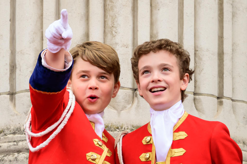 TOPSHOT - Britain's Prince George of Wales (L) points next to another page, as they stand on the Buckingham Palace in London, following the coronations of King Charles III and Queen Camilla, on May 6, 2023. - The set-piece coronation is the first in Britain in 70 years, and only the second in history to be televised. Charles will be the 40th reigning monarch to be crowned at the central London church since King William I in 1066. Outside the UK, he is also king of 14 other Commonwealth countries, including Australia, Canada and New Zealand. Camilla, his second wife, will be crowned queen alongside him, and be known as Queen Camilla after the ceremony. (Photo by Leon Neal / POOL / AFP) / 