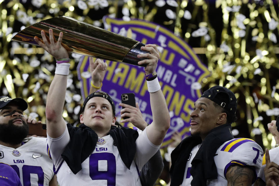 LSU quarterback Joe Burrow holds the trophy as safety Grant Delpit looks on after a NCAA College Football Playoff national championship game against Clemson, Monday, Jan. 13, 2020, in New Orleans. LSU won 42-25. (AP Photo/Sue Ogrocki)