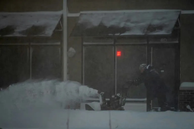 A man uses a snow blower to clear snow at a strip mall in Stony Brook, New York during a blizzard that hit the Northeastern United States on January 29, 2022 (AFP/Andrew Theodorakis)