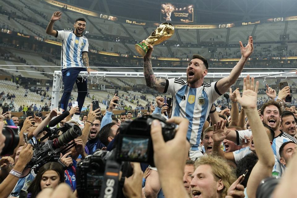 FILE - Argentina's Lionel Messi celebrates with the trophy in front of fans after winning the World Cup final soccer match between Argentina and France at the Lusail Stadium in Lusail, Qatar, Dec. 18, 2022. A World Cup that ended with Lionel Messi finally holding the golden trophy in his hands produced some unforgettable images from the staff of Associated Press photographers at the tournament in Qatar. Through the 64 games over nearly a month of soccer, the AP deployed dozens of photographers to the eight stadiums in and around Doha.(AP Photo/Martin Meissner, File)