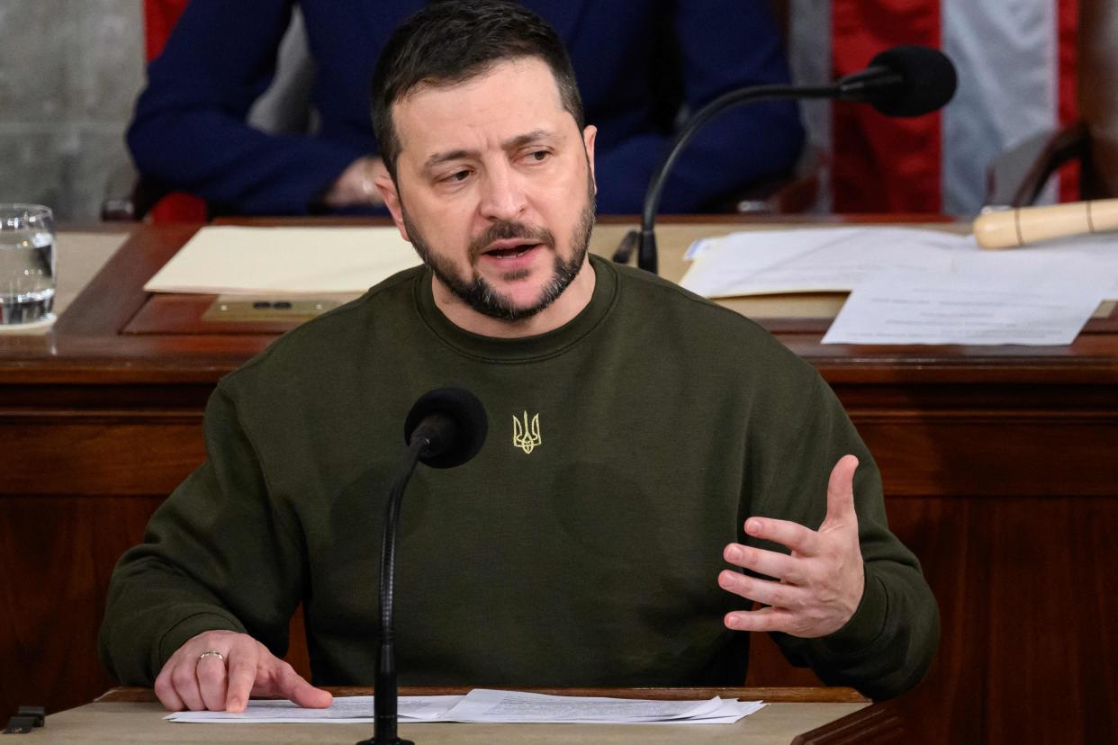 Ukrainian President Volodymyr Zelensky sits at a microphone while addressing Congress.