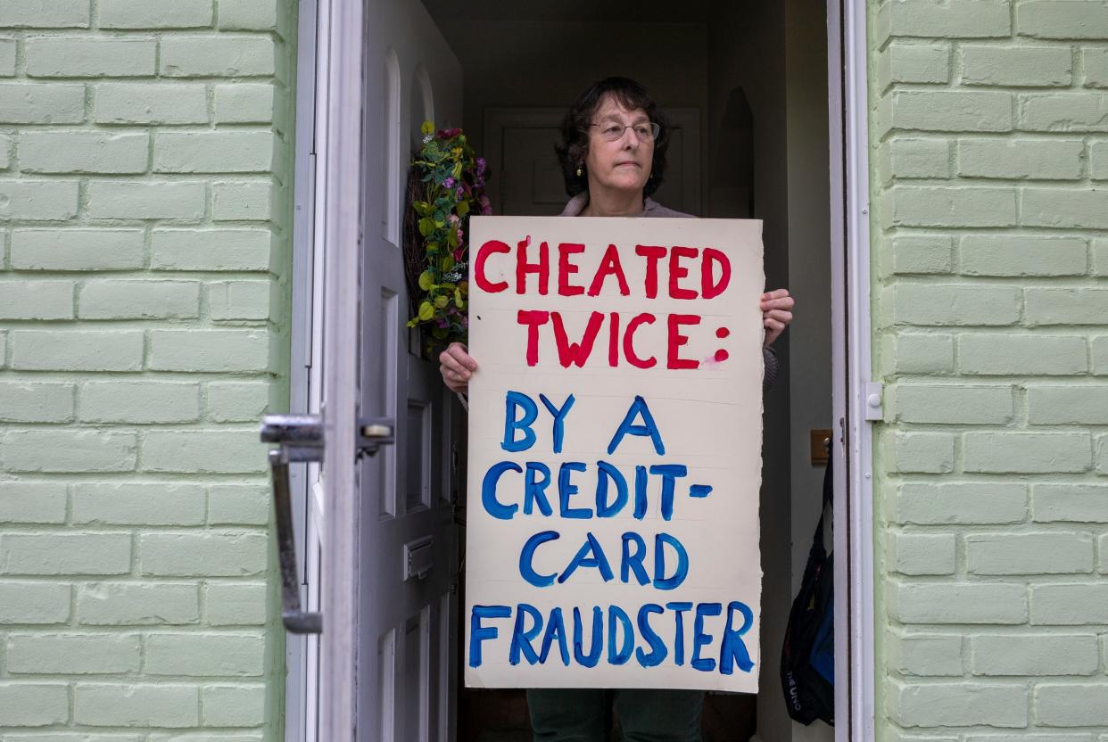Laura Dewey holds a sign in the door of her home in Grosse Pointe Woods on Thursday, April 4, 2024. Dewey claims that scammers bought eight tickets to a concert in Alabama using her credit card number and her credit union denied her claim as she disputed the charges.