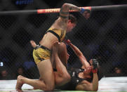 Amanda Nunes, top, goes to strike Julianna Pena during a mixed martial arts women's bantamweight title bout at UFC 277 on Saturday, July 30, 2022, in Dallas. (AP Photo/Richard W. Rodriguez)