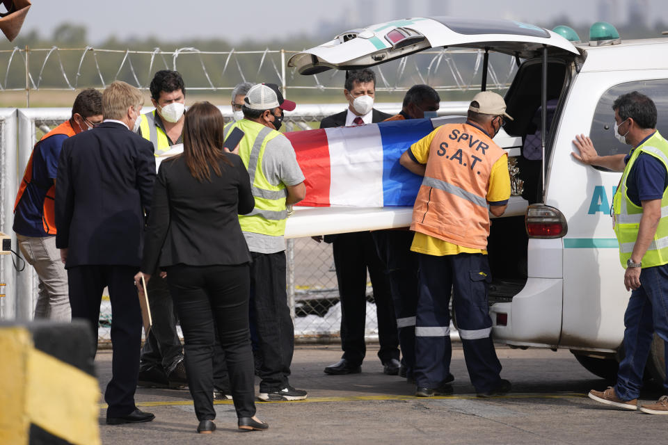 Airport workers remove a flag draped coffin carrying the remains of Lady Luna at Silvio Pettirossi airport in Luque, Paraguay, Tuesday, July 13, 2021. Lady Luna was a nanny working for the sister of Paraguayan first lady Silvana Lopez Moreira, and was removed from the Champlain Towers South condominium in Surfside, Florida, which collapsed on June 24. (AP Photo/Jorge Saenz)