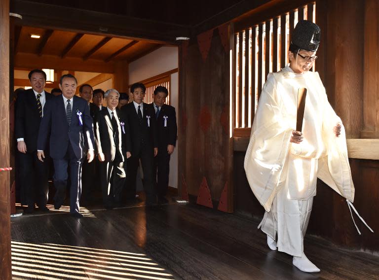 Japanese lawmakers follow a Shinto priest (R) during a visit to the controversial Yasukuni shrine on October 17, 2014