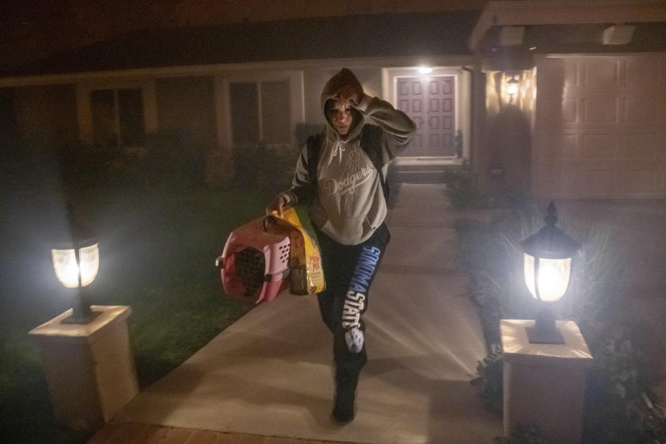 A woman evacuates her home with her cat as the Saddleridge fire threatens homes in Granada Hills, Calif., Friday, Oct. 11, 2019. (AP Photo/Michael Owen Baker)