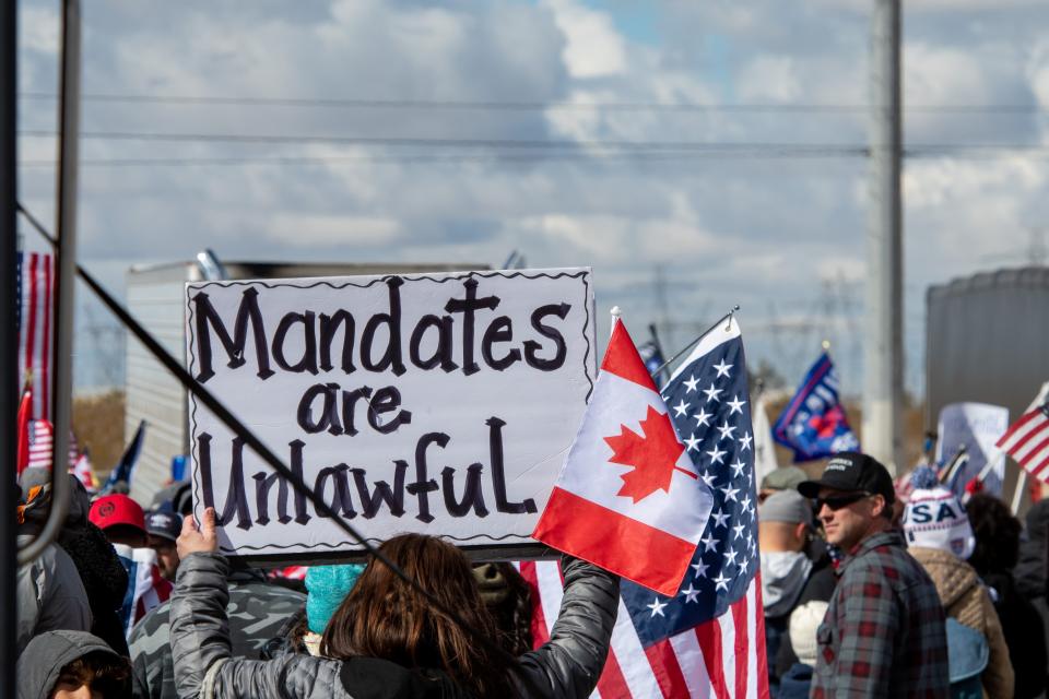 An attendee holds a sign at the People's Convoy rally, a movement opposing COVID-19 mandates, in Adelanto Stadium in Adelanto on Wednesday, Feb. 23, 2022.