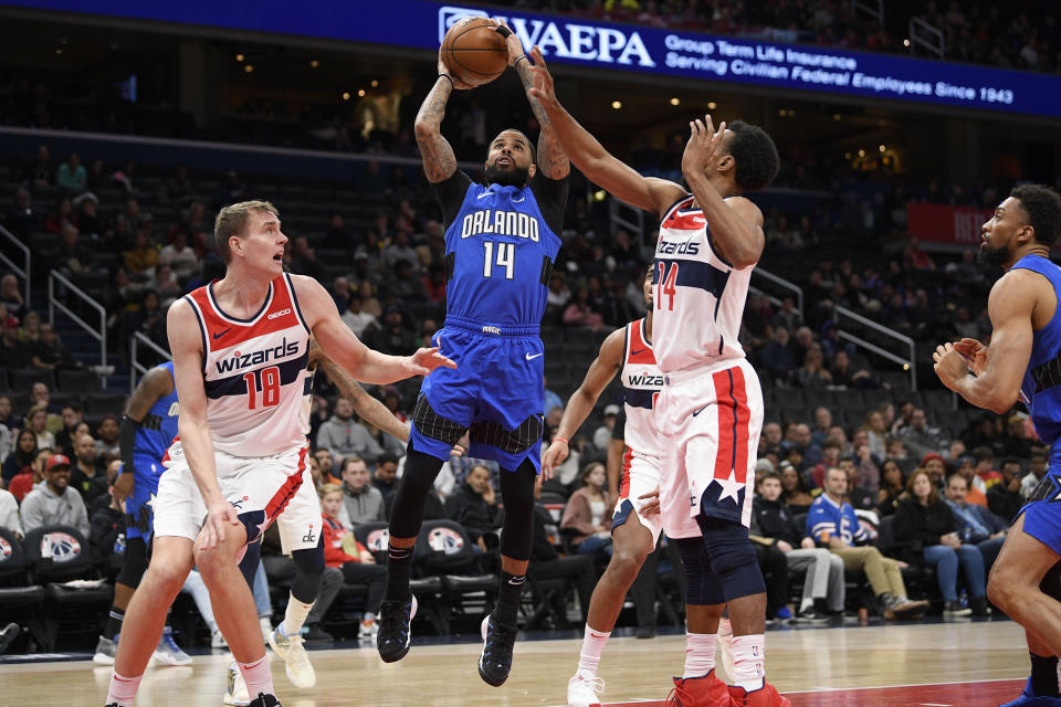 Orlando Magic guard D.J. Augustin (14) goes to the basket between Washington Wizards center Anzejs Pasecniks (18) and guard Ish Smith (14) during the first half of an NBA basketball game Wednesday, Jan. 1, 2020, in Washington. (AP Photo/Nick Wass)