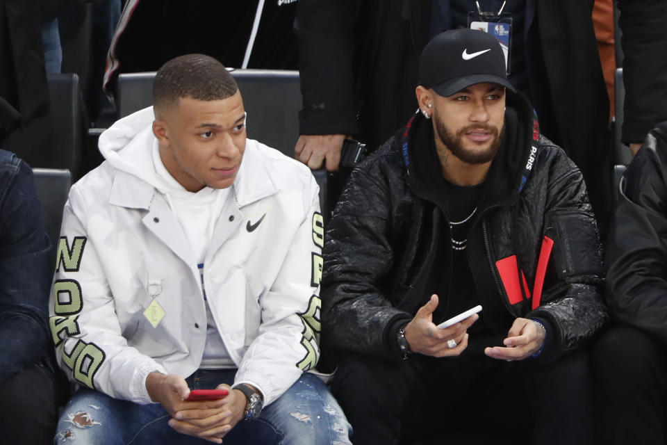 Paris St Germain's players Kylian Mbappe, left, and Neymar attend the NBA basketball match Milwaukee Bucks against Charlotte Hornets, in Paris, Friday, Jan. 24, 2020. (AP Photo/Thibault Camus)