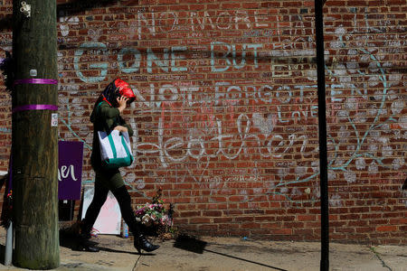 A woman walks past tributes written at the site where Heather Heyer was killed during the 2017 white-nationalist rally in Charlottesville, Virginia, U.S., August 1, 2018. REUTERS/Brian Snyder