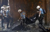 Police carry a cadaver bag containing a charred body of a worker killed during a fire at a slipper factory in Valenzuela, Metro Manila in the Philippines May 14, 2015.A fire at a factory making rubber slippers killed 31 workers in the Philippine capital on Wednesday, and dozens were missing and feared dead, officials said. REUTERS/Erik De Castro