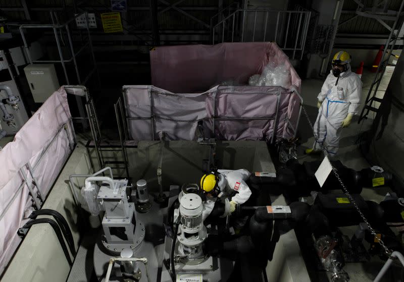 Employees of TEPCO wearing protective suits and masks are seen inside a radiation filtering ALPS at tsunami-crippled Fukushima Daiichi nuclear power plant in Okuma town, Japan