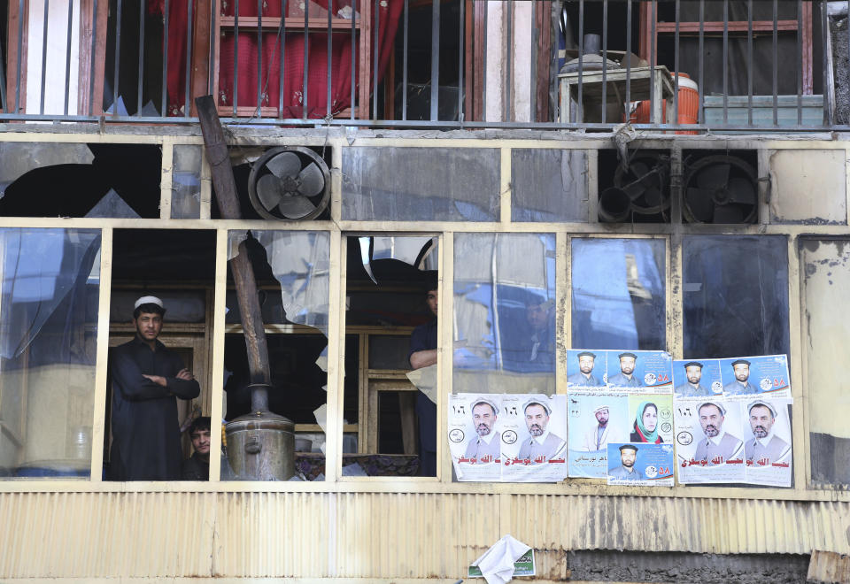 An Afghan man peers through broken glass windows of a building after a multi-pronged attack on a police station in Jalalabad, the capital of eastern Nangarhar province, Afghanistan, Thursday, March 20, 2014. Taliban insurgents staged the attack, using a suicide bomber and gunmen to lay siege to the station, government officials said. Two remotely detonated bombs also exploded nearby. (AP Photo/Rahmat Gul)