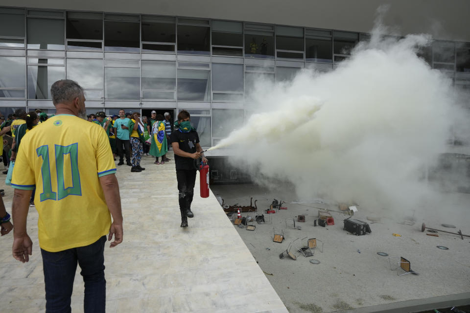 A protester, supporter of Brazil's former President Jair Bolsonaro, empties a fire extinguisher after protesters stormed Planalto Palace in Brasilia, Brazil, Sunday, Jan. 8, 2023. Planalto is the official workplace of the president. (AP Photo/Eraldo Peres)