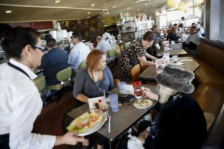 Manger Mel Lara, far right, smiles at an elderly customer's dog under the table as they dine at Norms Diner on La Cienega Boulevard in Los Angeles, California May 20, 2015. REUTERS/Patrick T. Fallon