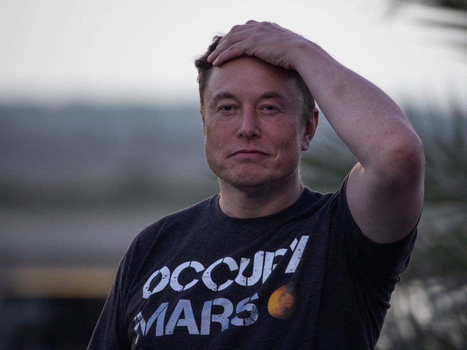 elon musk frowning smirking with hand on top of head wearing black occupy mars shirt