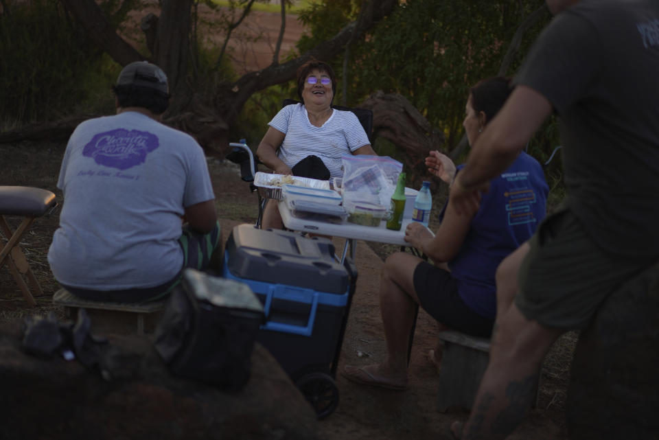 From left, Eddie Topenio, his wife, Sonia Topenio, Roz Choi, and Kanani Santos share a meal after working in the Hanapepe salt patch on Sunday, July 9, 2023, in Hanapepe, Hawaii. (AP Photo/Jessie Wardarski)