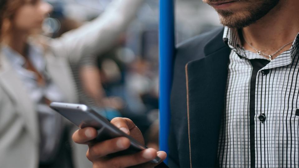 A guy looking at his phone on the subway.