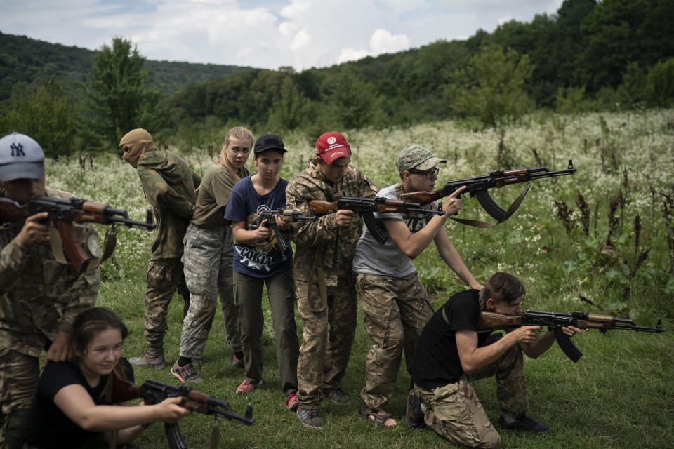 In this July 29, 2018 photo, young participants of the "Temper of will" summer camp, organized by the nationalist Svoboda party, practice tactical formations with AK-47 assault riffles in a village near Ternopil, Ukraine. (AP Photo/Felipe Dana)