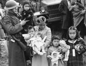 <p>Mrs. Shigeho Kitamoto had no time for tears when she was evacuated along with other Japanese from Bainbridge Island in Washington State, March 30, 1942. She has too busy looking after her four children. Corporal George Bushy, member of the military guard which supervised the departure of 237 Japanese for California, gave her a hand with the youngest. (AP Photo) </p>