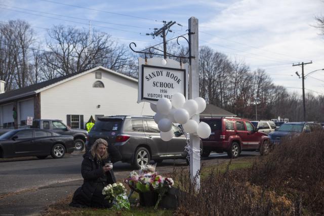One day after 26 children and adults were murdered at Sandy Hook Elementary School on Dec. 14, 2012, a woman visits a makeshift memorial there