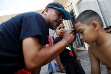 A boy, a member of a migrants caravan from Central America, gets his hair cut at the end of the caravan journey through Mexico, prior to preparations for an asylum request in the U.S., in Tijuana, Baja California state, Mexico April 26, 2018. REUTERS/Edgard Garrido