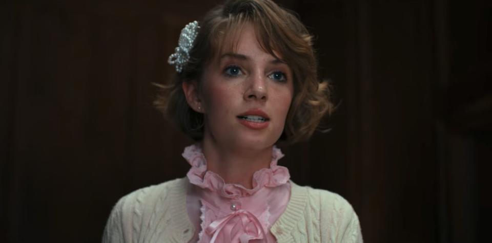 maya hawke as robin in stranger things, with a passionate expression on her face and wearing a frilly pink collar