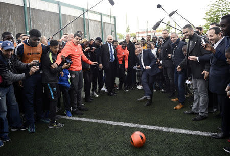 Emmanuel Macron (C), head of the political movement En Marche !, or Onwards !, and candidate for the 2017 presidential election, kicks a soccer ball during a campaign visit in Sarcelles, near Paris, April 27, 2017. REUTERS/Martin Bureau