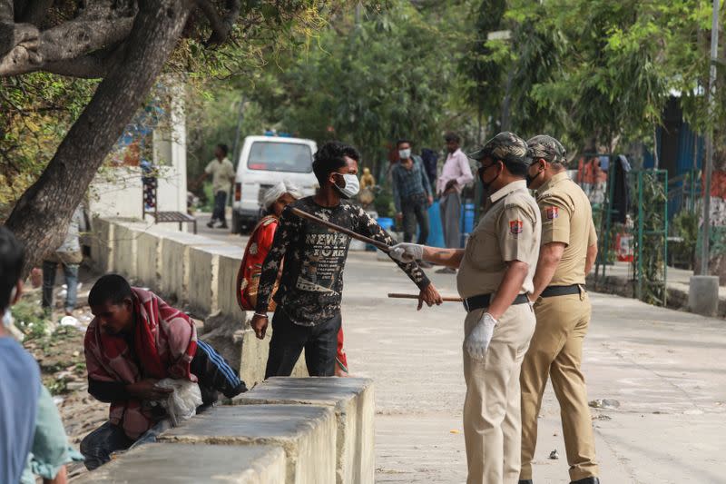 A police officer wields his baton against a man as a punishment outside a government-run night shelter during a 21-day nationwide lockdown to limit the spreading of coronavirus disease (COVID-19), in the old quarters of Delhi