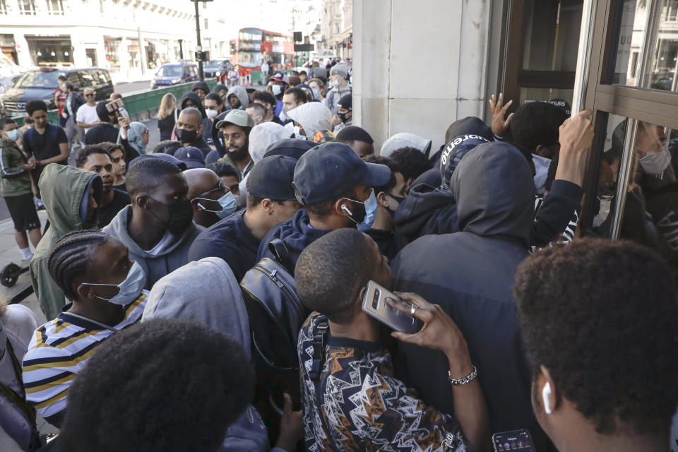 People queueing push to enter the Niketown shop in London, Monday, June 15, 2020. After three months of being closed under coronavirus restrictions, shops selling fashion, toys and other non-essential goods are being allowed to reopen across England for the first time since the country went into lockdown in March.(AP Photo/Matt Dunham)