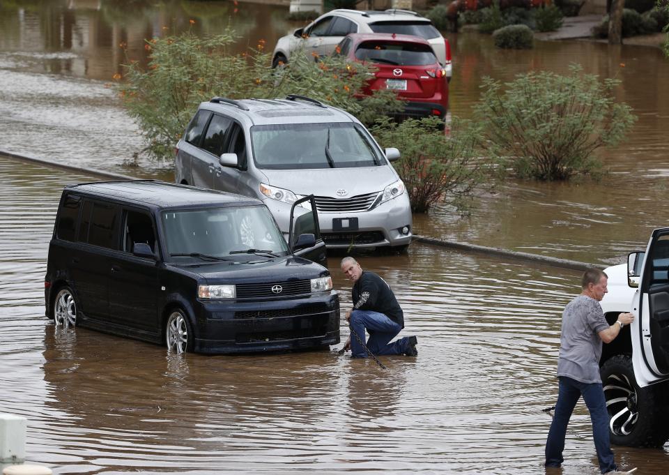 A car owner waits to get towed from a flooded street as several other vehicles are left stranded during a flash flood as a result of heavy rains from tropical storm Rosa Tuesday, Oct. 2, 2018, in Phoenix. (AP Photo/Ross D. Franklin)