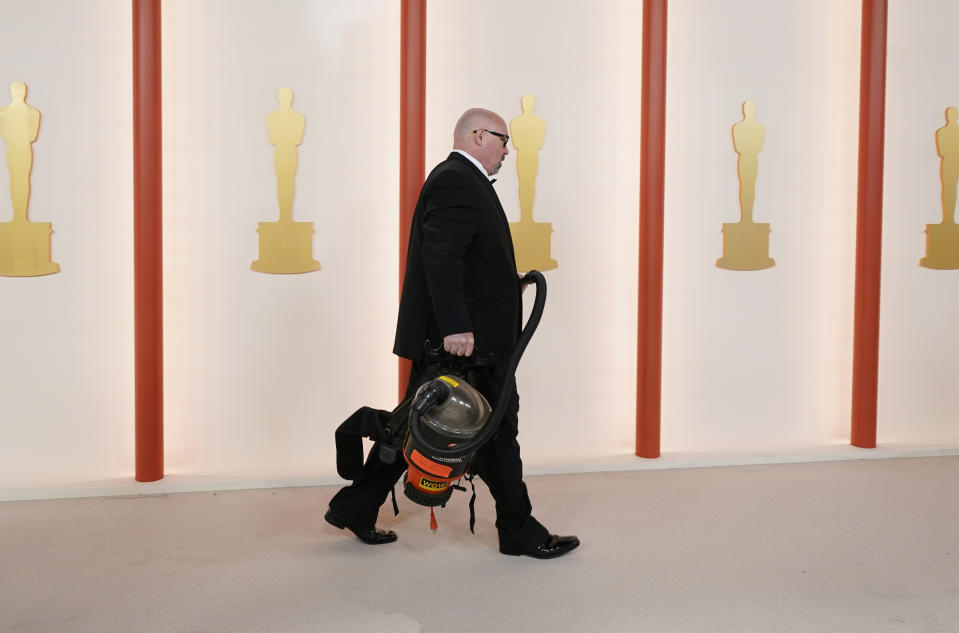 Event staff vacuums the carpet at the Oscars on Sunday, March 12, 2023, at the Dolby Theatre in Los Angeles. (AP Photo/Ashley Landis)