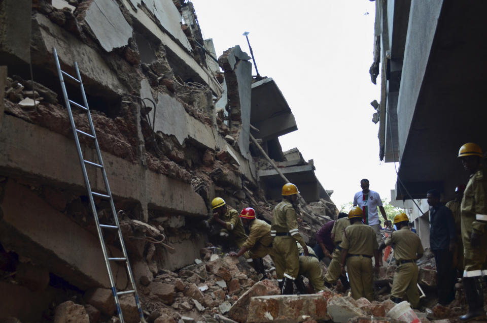 Rescue workers stand amid the debris of a building that collapsed in Canacona, a city about 70 kilometers (44 miles) from the state capital of Panaji, India, Saturday, Jan. 4, 2014. A five-story building under construction in the southern Indian state of Goa collapsed on Saturday, killing at least seven workers and leaving dozens more feared trapped under the rubble, police said. (AP Photo)