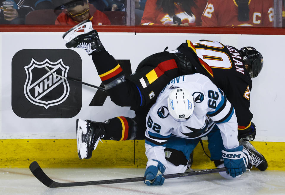 San Jose Sharks forward Kevin Labanc (62) checks Calgary Flames forward Blake Coleman during the second period of an NHL hockey game in Calgary, Alberta, Saturday, March 25, 2023.(Jeff McIntosh/The Canadian Press via AP)