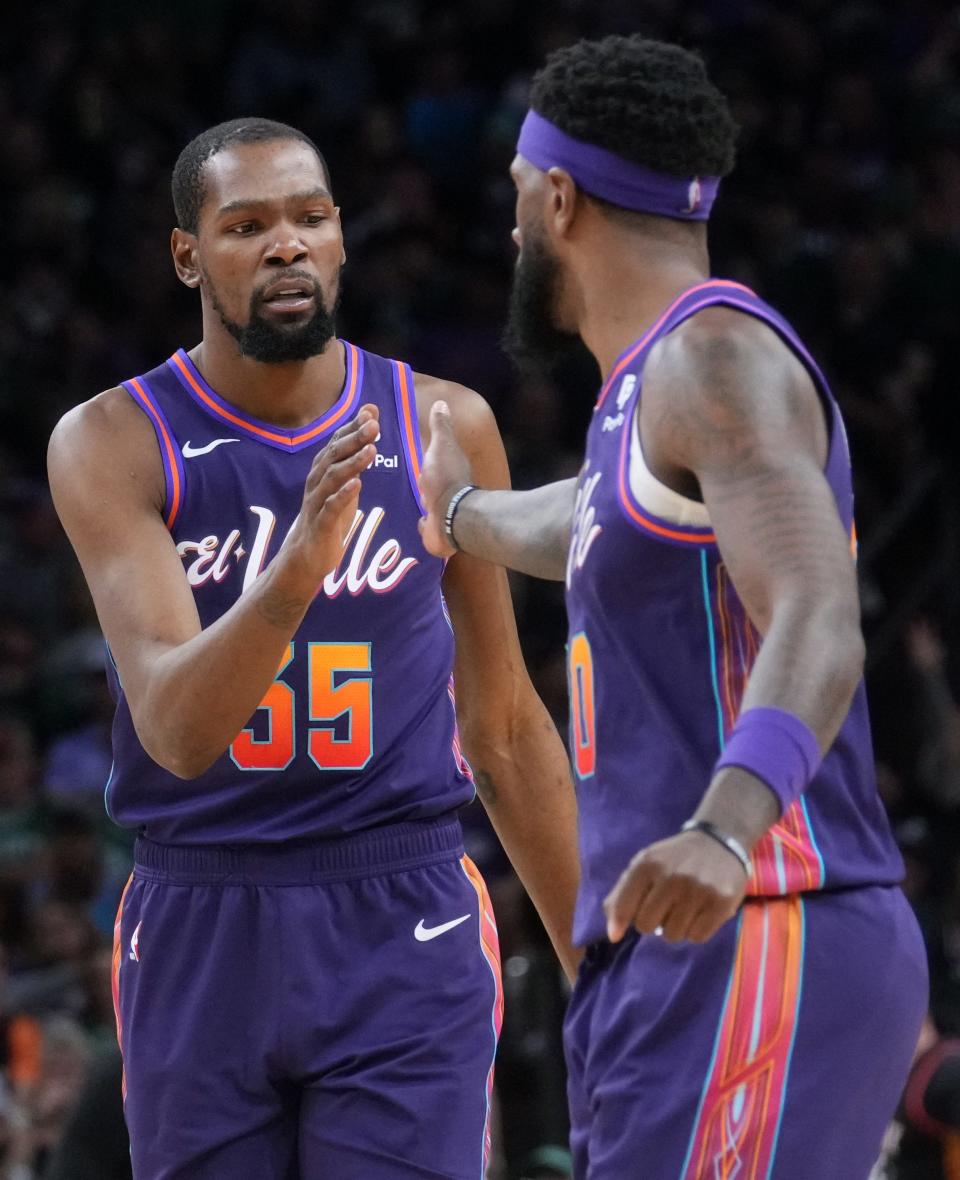 Phoenix Suns forwards Kevin Durant (35) and Royce O'Neale (00) high-five during their game against the Boston Celtics at Footprint Center.