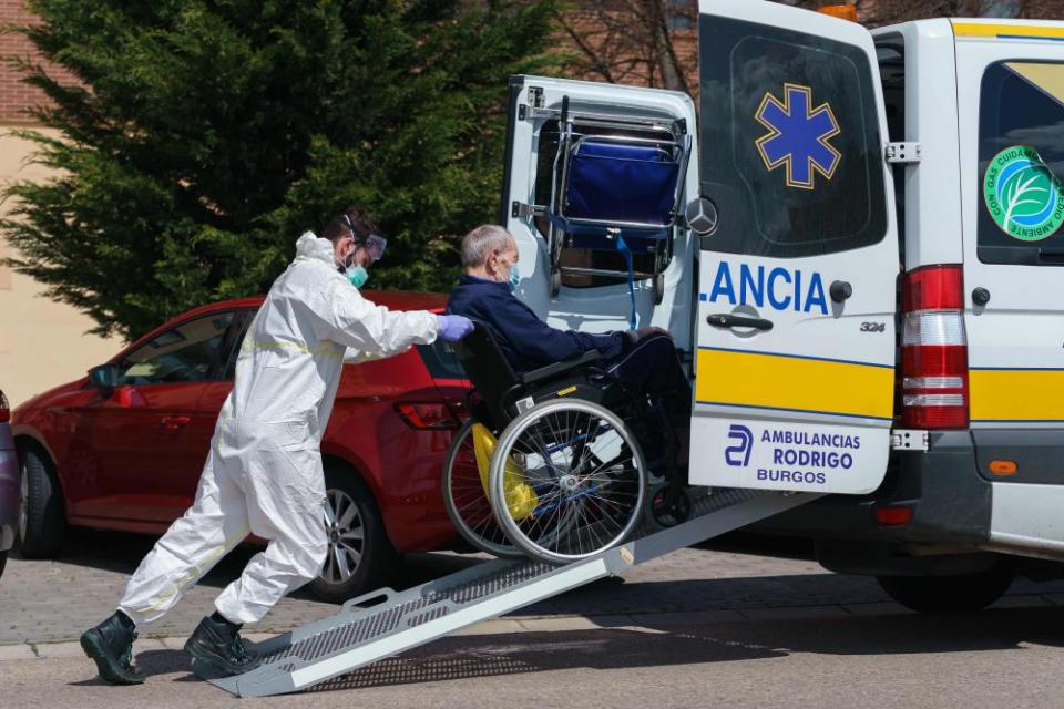 A worker pushes a man on a wheelchair outside an elderly people’s nursing home in Burgos in northern Spain on Thursday.