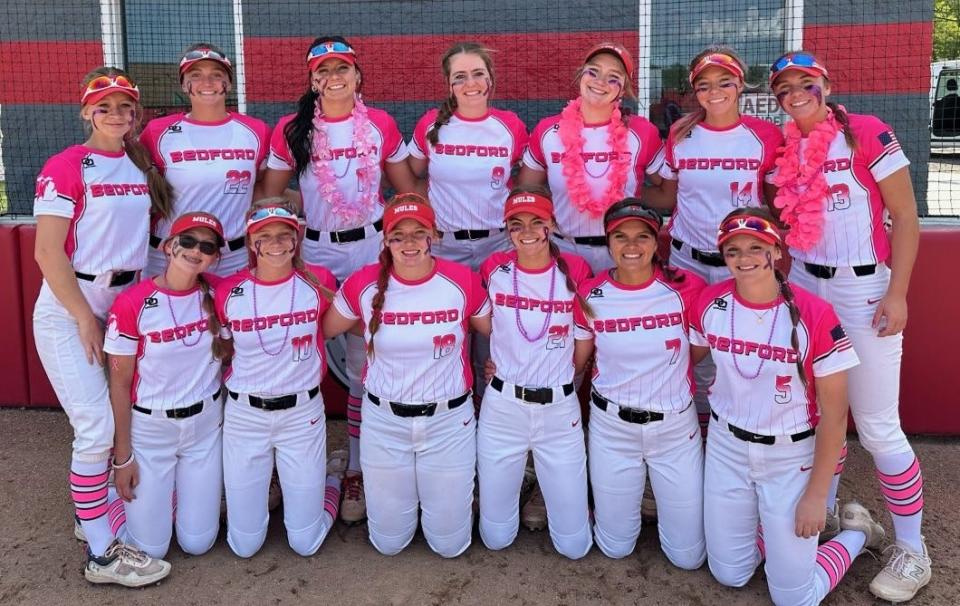 Bedford's softball team models the pink uniforms they wore Monday to honor assistant coach Kendra Dunlap.