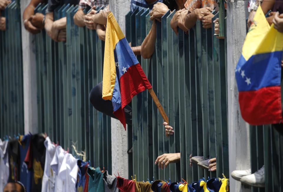 A supporter of Venezuela's opposition leader and self-proclaimed interim president Juan Guaidó gholds a national flag at a rally in Guatire, Venezuela, Saturday, May 18, 2019. (AP Photo/Ariana Cubillos)