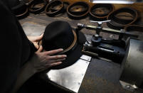 A man holds a hat inside the Borsalino hat factory, in Spinetta Marengo, near Alessandria, Italy, Thursday, Jan. 17, 2019. Borsalino's prized felt hats are handmade by 80 workers in its Piemonte factory, many who have worked there for decades, with original machinery that use hot water and steam to transform rabbit fur into highly prized felt, that is formed into clochards, dyed and molded by hand to create the latest styles. (AP Photo/Antonio Calanni)