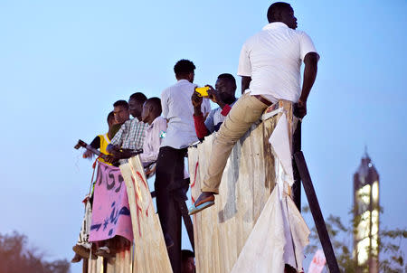 Demonstrators sit on a torn billboard as they attend a protest rally demanding Sudanese President Omar Al-Bashir to step down outside Defence Ministry in Khartoum, Sudan April 10, 2019. REUTERS/Stringer